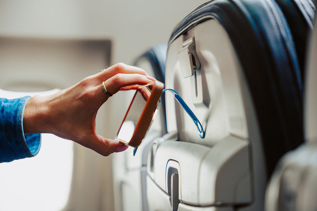 Attaching the Blue Mo'Bettah Airplane Phone Holder to an airplane seat pocket for hands-free viewing