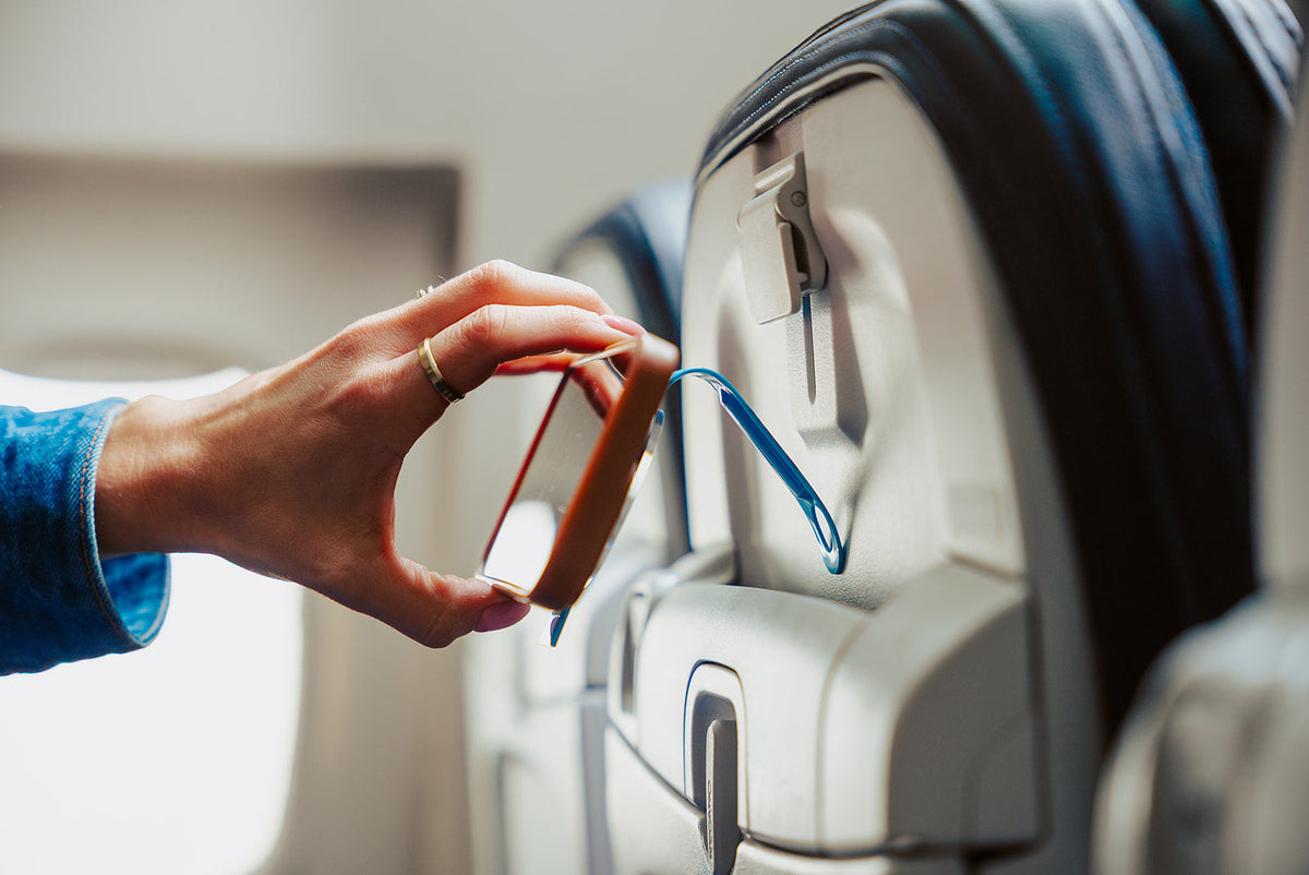 Attaching the Blue Mo'Bettah Airplane Phone Holder to an airplane seat pocket for hands-free viewing
