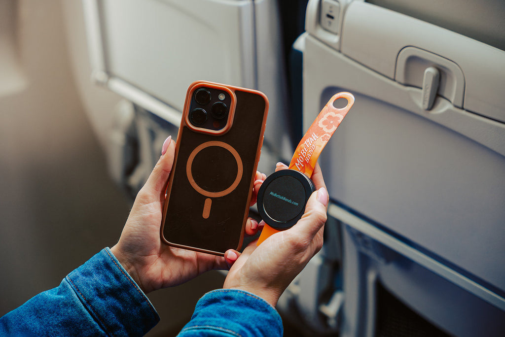 Orange Mo'Bettah Airplane Phone Holder attached to a MagSafe-compatible iPhone