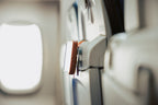 Orange Mo'Bettah Airplane Phone Holder holding an iPhone on an airplane seat pocket during a flight